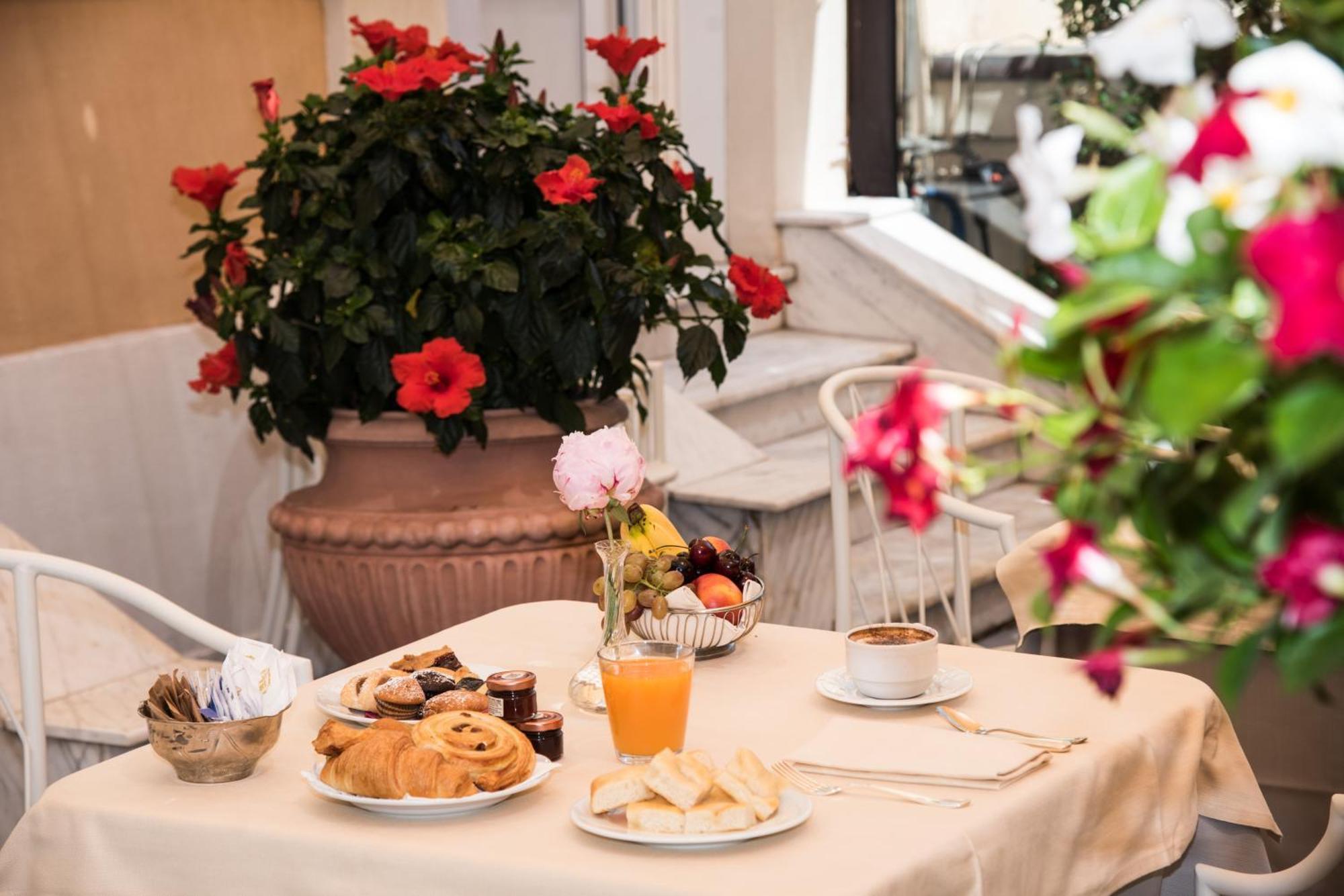 Hotel Bristol Palace Genoa Bagian luar foto The photo shows a charming breakfast setup on a table covered with a light-colored tablecloth. There is a variety of food items, including pastry items like croissants and sweet rolls, alongside some fruit. Also visible is a small glass of orange jui