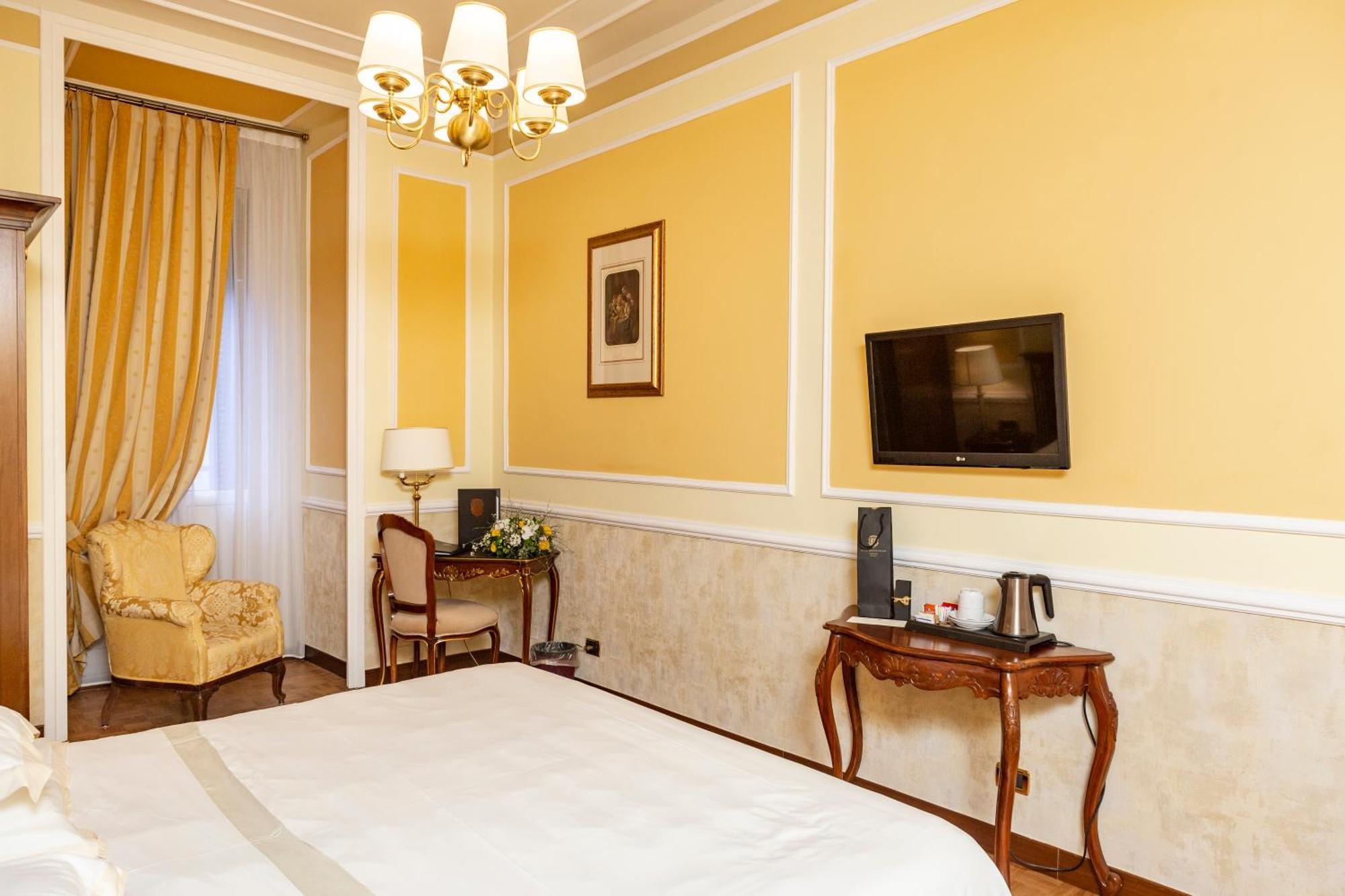 Hotel Bristol Palace Genoa Ruang foto The photo shows an interior of a hotel room. The walls are painted a warm yellow color, and there's a chandelier hanging from the ceiling. On one side, there's a large window draped with elegant curtains. A comfortable armchair is situated in the cor